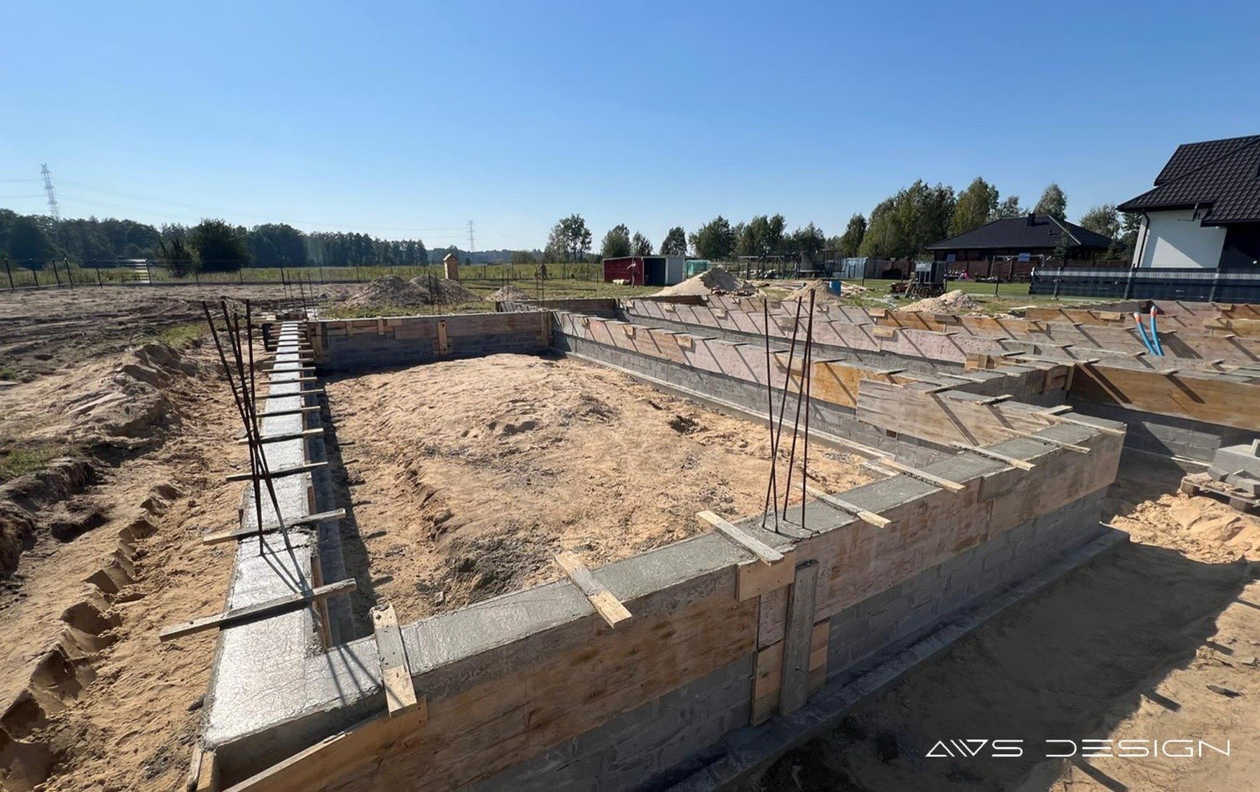 Plac budowy: ściany fundamentowe z bloczków, wieniec żelbetowy w szalunku, pręty zbrojeniowe